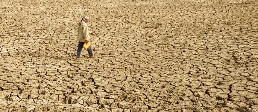 A man walking through dried mud in a drought